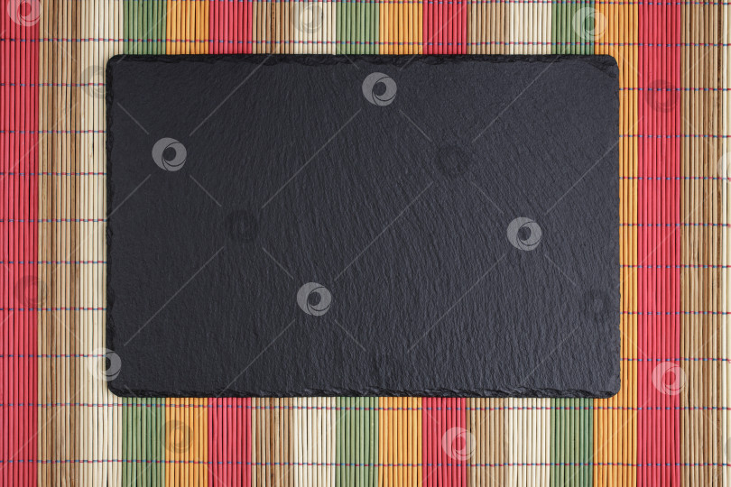 Скачать Черное сланцевое блюдо на разноцветном коврике bomboo фотосток Ozero