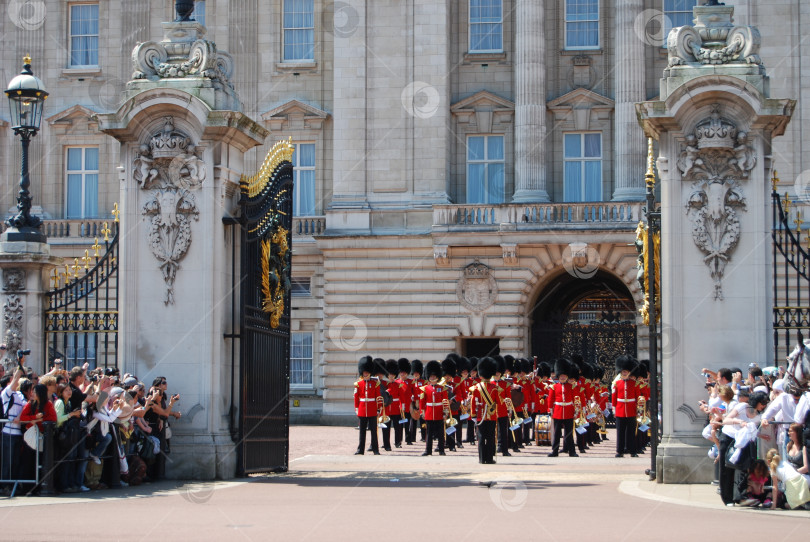 Скачать Лондон, Англия, Великобритания, 24 мая 2009 года. Военный оркестр в красных мундирах стоит за открытыми воротами Букингемского дворца. фотосток Ozero