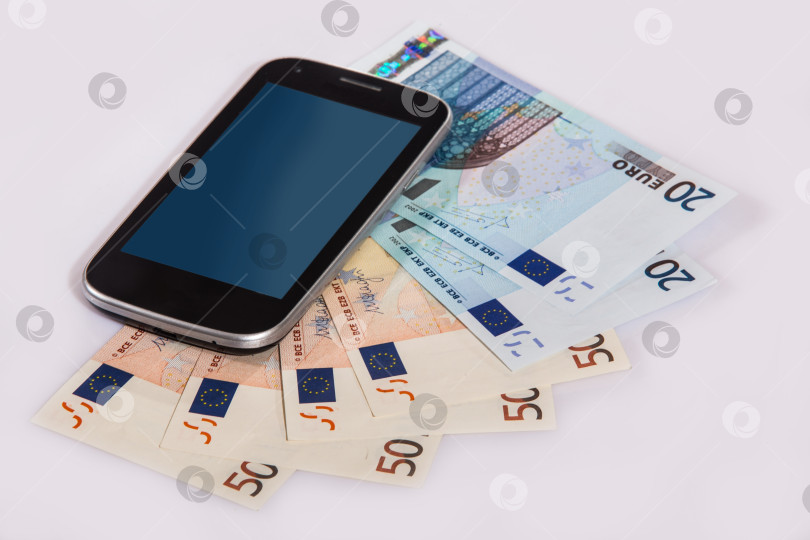 Скачать Мобильный телефон лежит на банкнотах евро. фотосток Ozero