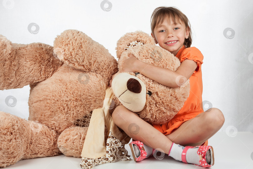 Скачать Милая маленькая девочка играет со своим другом большим меховым медведем. Малышка обнимает своего плюшевого мишку. Милая маленькая девочка играет со своим другом большим меховым медведем. Малышка обнимает своего плюшевого мишку фотосток Ozero