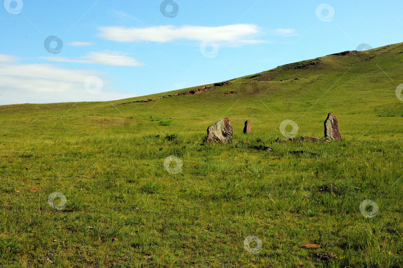 Скачать Группа древних каменных плит на склоне холма, поросшем травой, в теплый летний день. фотосток Ozero