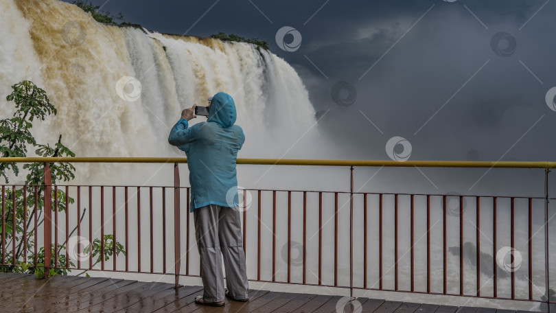 Скачать Мужчина стоит на смотровой площадке у водопада. фотосток Ozero