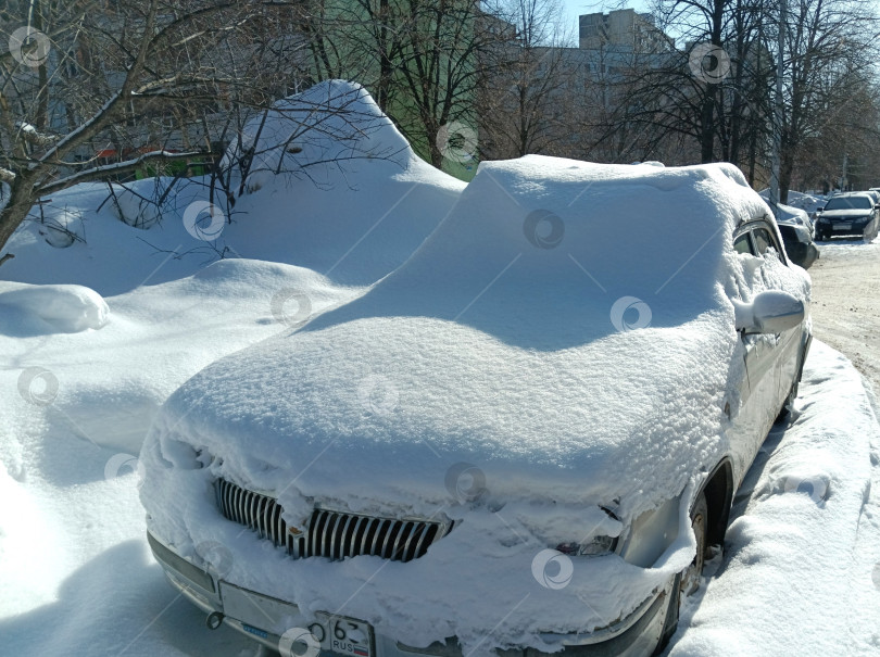 Скачать Брошенный автомобиль занесен снегом после сильной метели в городе фотосток Ozero