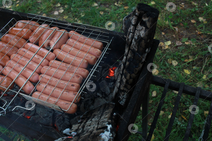 Скачать сосиски в гриле на решетке. Еда на свежем воздухе. фотосток Ozero