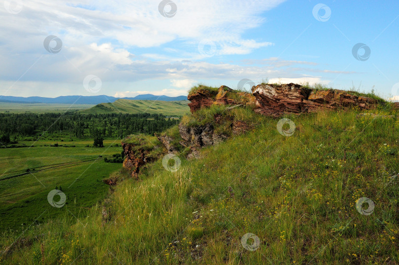 Скачать Необычные слоистые каменные образования на вершине холма с видом на бесконечную живописную долину теплым летним днем. фотосток Ozero