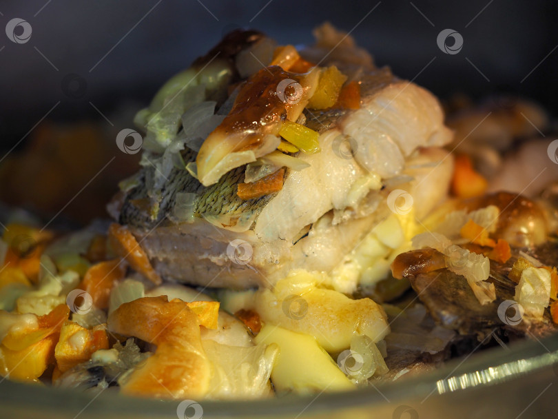 Скачать Рыба, запеченная в духовке с овощами и соусом в стеклянной миске. Готовое рыбное блюдо. Фото для фона. фотосток Ozero