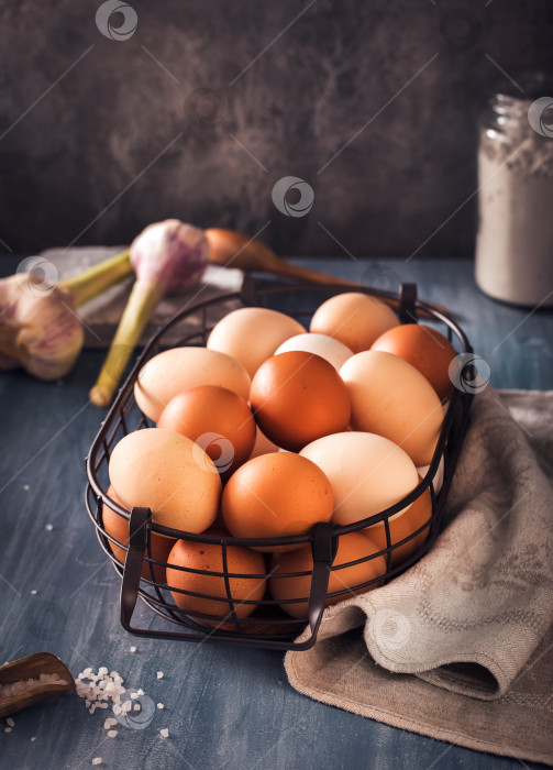 Скачать Яйца в проволочной корзинке на деревенском столе фотосток Ozero