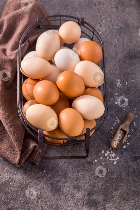 Скачать Яйца в проволочной корзинке на сером фоне, вид сверху фотосток Ozero