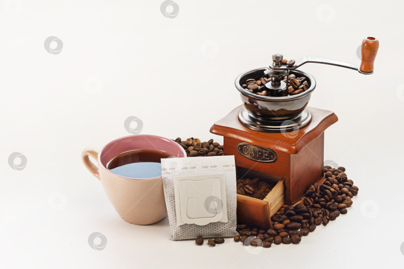 Скачать Фильтр-пакет с молотым кофе, ручная кофемолка и чашка кофе эспрессо на белом фоне. Место для копирования фотосток Ozero
