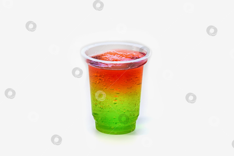 Скачать Красное и зеленое желе в пластиковом стаканчике на белом фоне. Сладкий желейный десерт фотосток Ozero