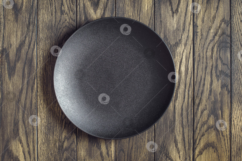 Скачать Пустая черная тарелка на деревянном фоне фотосток Ozero