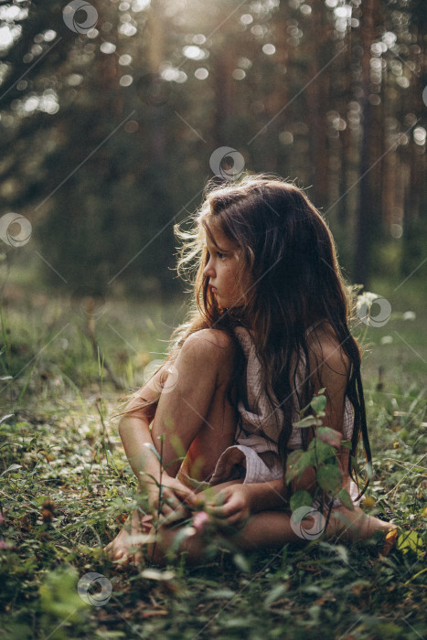 Скачать Девочка сидит в траве на лесной поляне фотосток Ozero