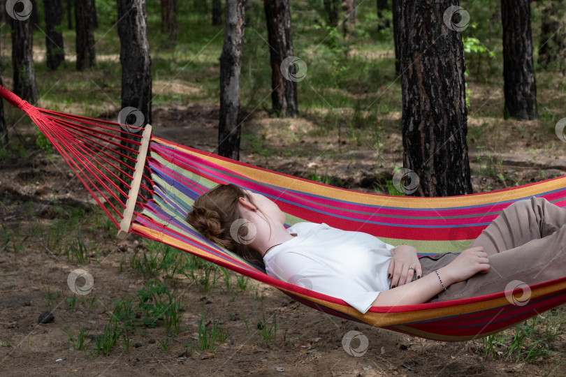 Скачать Красивая молодая женщина отдыхает в гамаке в лесу. Летний пейзаж, прекрасное утро на лоне природы. Девушка любуется видами и природой. Подышала свежим воздухом. Прекрасный утренний свет. фотосток Ozero