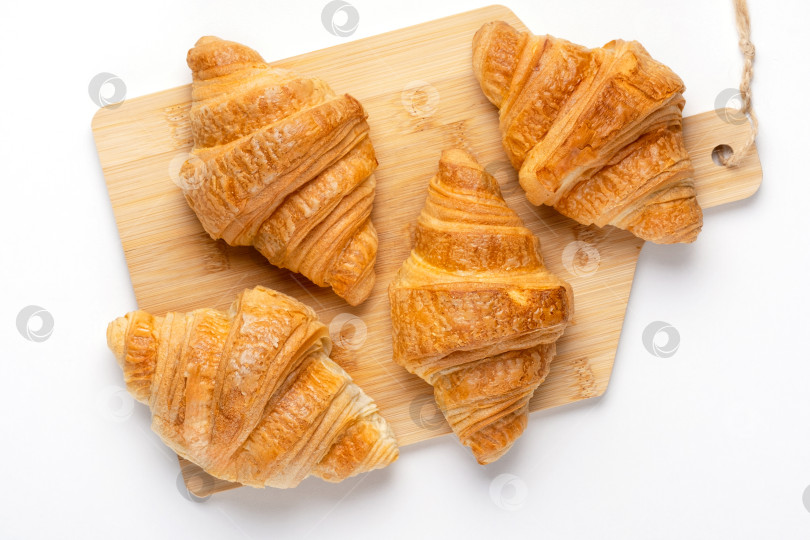 Скачать Французские круассаны на завтрак. Свежеиспеченные круассаны на разделочной доске, выделенные на белом фоне, вид сверху фотосток Ozero