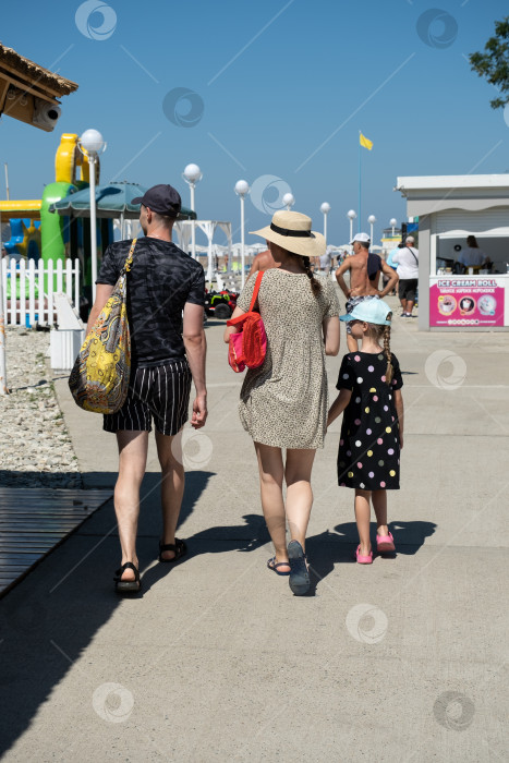 Скачать Молодая семья прогуливается по набережной в курортном поселке Небуг, Краснодарский край, Россия - 1 июля 2021 года фотосток Ozero