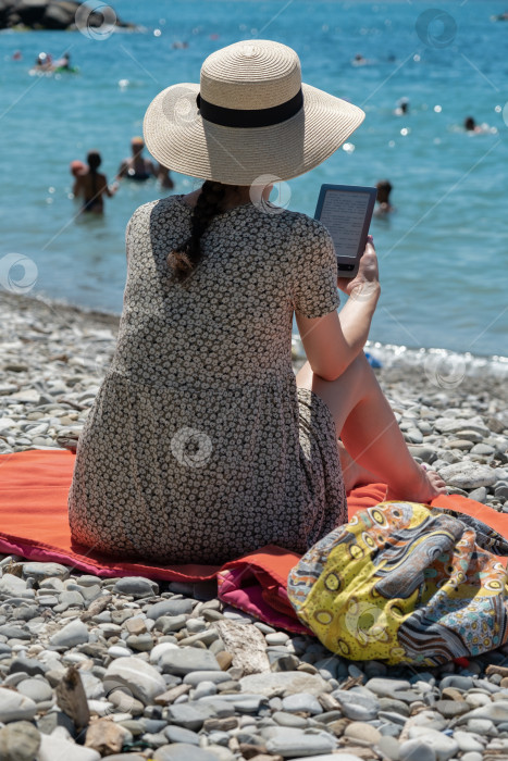 Скачать Крупный план брюнетки, читающей книгу на пляже, вид с пляжа фотосток Ozero