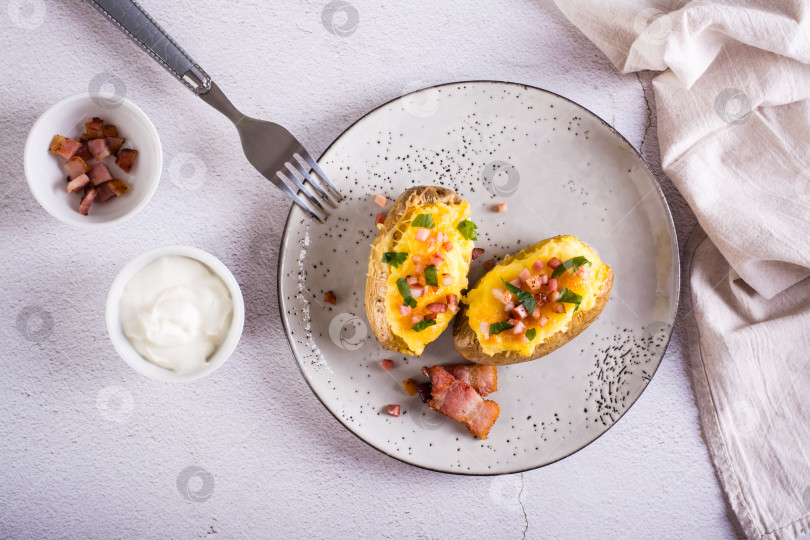 Скачать Дважды запеченный картофель с беконом и сыром на тарелке на столе. Домашний ужин. Вид сверху фотосток Ozero