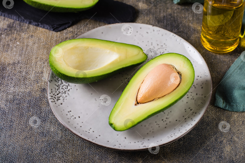 Скачать Половинки авокадо на тарелке на столе. Здоровое витаминное питание. фотосток Ozero