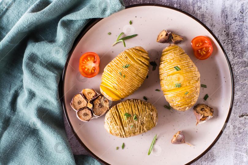 Скачать Вкусный домашний запеченный картофель с чесноком и розмарином на тарелке. Вид сверху. Крупным планом фотосток Ozero