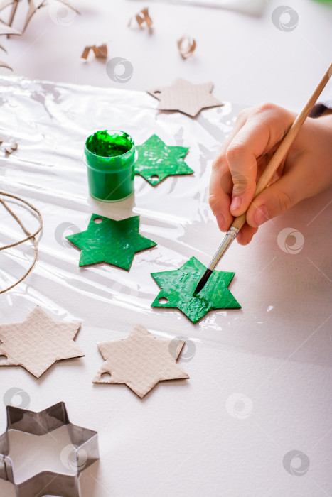 Скачать Детские руки раскрашивают картонную звезду для рождественских украшений ручной работы своими руками. Вертикальный вид. фотосток Ozero