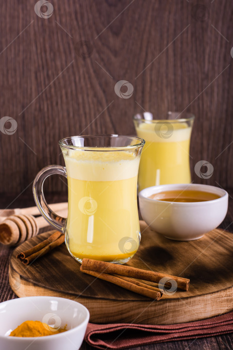Скачать Полезное золотистое молоко с куркумой и медом в стаканах на столе. Домашнее блюдо. Вид сверху фотосток Ozero