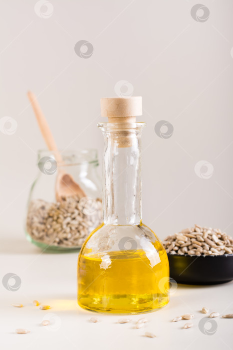 Скачать Органическое подсолнечное масло в бутылке и семечки в миске на столе. Вегетарианская еда. Вид по вертикали фотосток Ozero