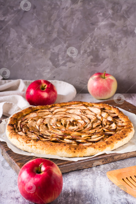 Скачать Пирог с запеченными яблоками на бумаге для выпечки на столе. Домашняя выпечка. Вертикальный вид фотосток Ozero