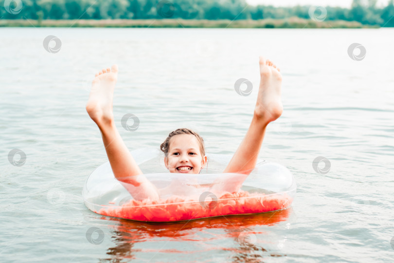 Скачать Веселая девушка сидит на надувном кольце, высунув ноги в реку. Местный туризм фотосток Ozero