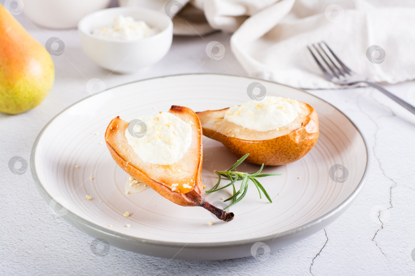 Скачать Запеченные груши с рикоттой, орехами, медом и розмарином на тарелке на столе. Домашний десерт. фотосток Ozero