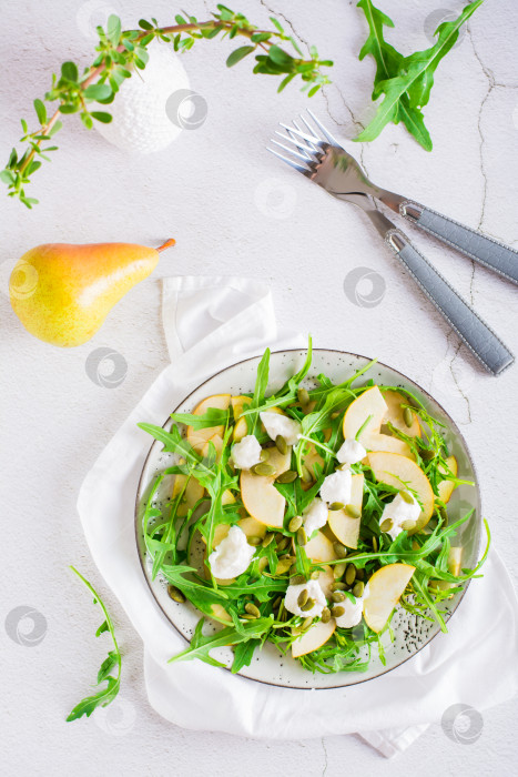 Скачать Свежий салат с грушами, рукколой, рикоттой и тыквенными семечками на тарелке. Вид сверху и по вертикали фотосток Ozero