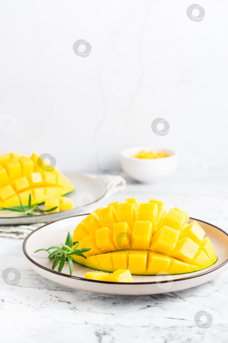 Скачать Кубики спелого манго на тарелках на столе. Тропический фрукт. Вертикальный вид фотосток Ozero