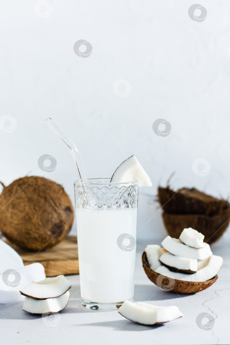 Скачать Кокосовое молоко в стакане и кусочки тропических фруктов на столе. Вертикальный вид фотосток Ozero