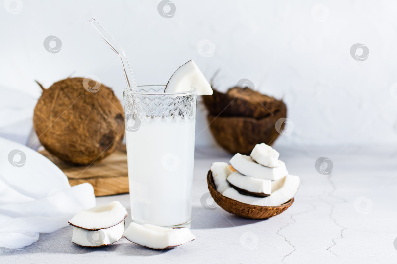 Скачать Кокосовое молоко в стакане с соломинкой и кусочками тропических фруктов на столе. фотосток Ozero