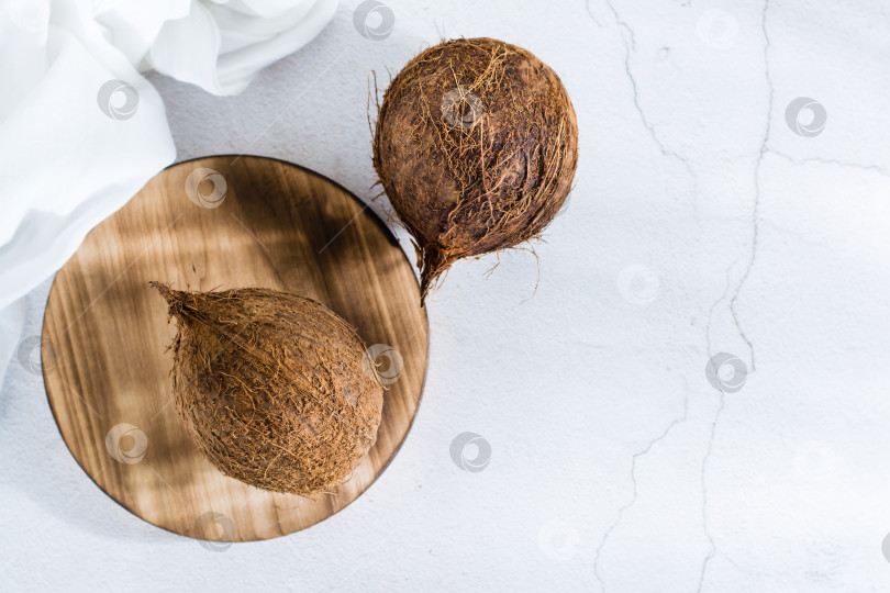 Скачать Два целых спелых кокосовых ореха на столе. Тропические фрукты. Вид сверху фотосток Ozero