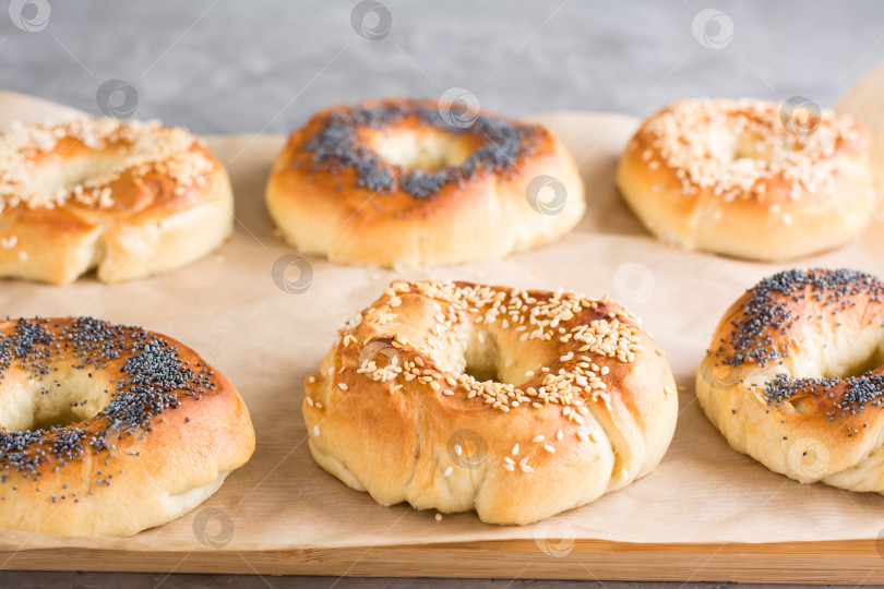 Скачать Запеченные рогалики с маком и кунжутом на пергаменте на столе. Домашняя выпечка фотосток Ozero