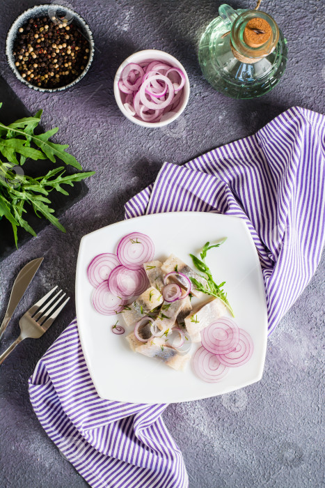 Скачать Нарезанная соленая сельдь в масле с луком и укропом на тарелке. Простая закуска. Вид сверху и по вертикали фотосток Ozero