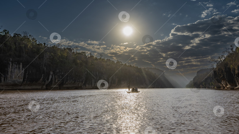 Скачать Пирога с туристами плывет по спокойной реке с крутыми берегами. фотосток Ozero