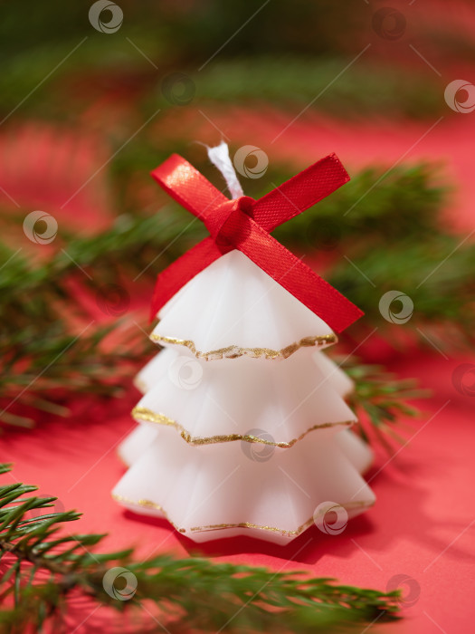 Скачать Свеча в форме рождественской елки и еловая ветка на красном фоне фотосток Ozero