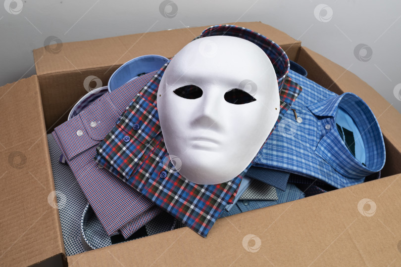 Скачать Белая маска лежит на рубашках в открытой картонной коробке - концепт на тему контрафактной продукции и контрабанды фотосток Ozero