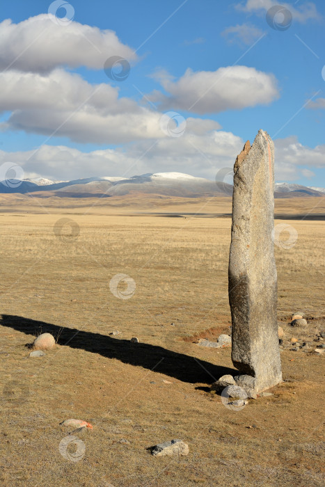 Скачать Высокий каменный менгир отбрасывает тень на бескрайнюю осеннюю степь. фотосток Ozero