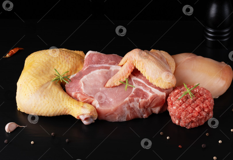 Скачать Различные виды сырого мяса - говядина, свинина, курица на черной деревянной доске фотосток Ozero