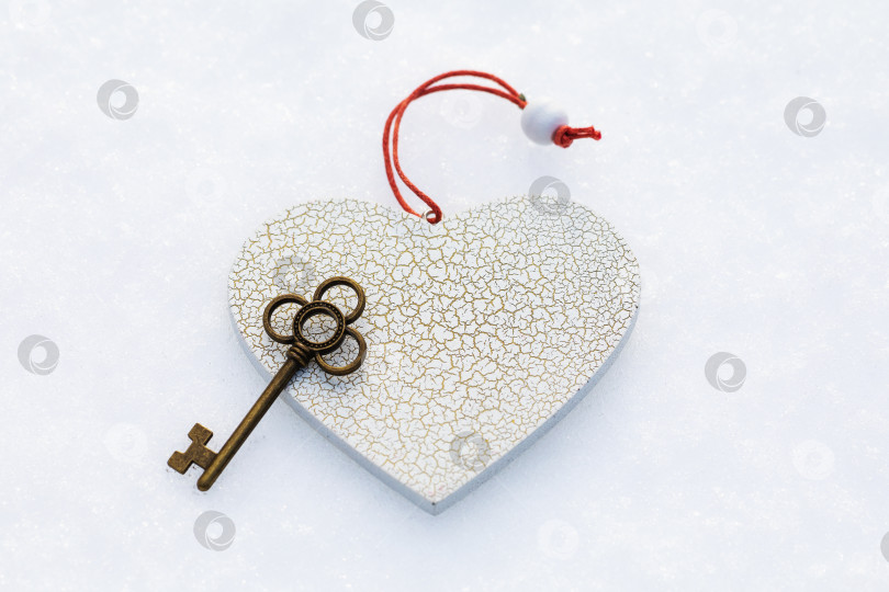 Скачать Игрушка в форме сердца и ключ на снегу, вид сверху фотосток Ozero