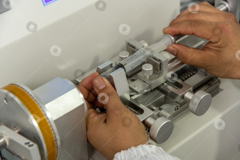 Скачать Снимок крупным планом рук, работающих на станке для производства шприцев на складе медицинского оборудования фотосток Ozero