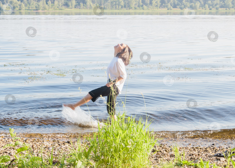 Скачать Молодая привлекательная женщина радуется летнему солнечному дню,гуляя по берегу реки фотосток Ozero