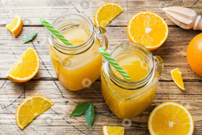 Скачать Апельсиновый сок в стеклянных банках и свежие апельсины на деревянном деревенском фоне. фотосток Ozero