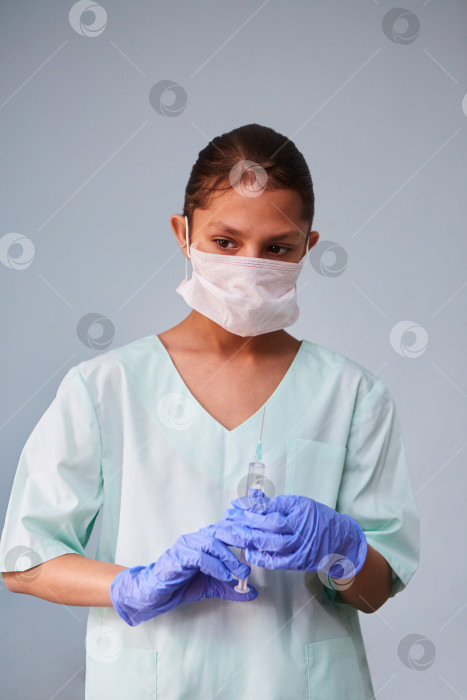 Скачать Девушка - молодая медсестра или ассистент в медицинской одежде и маске фотосток Ozero