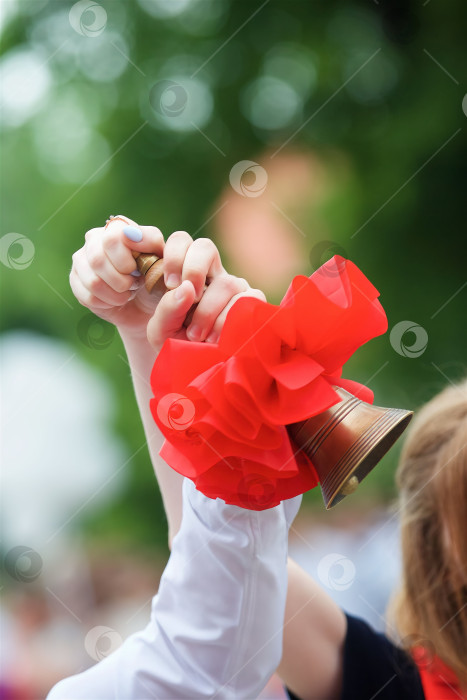 Скачать Руки школьников с колокольчиком на празднике в честь начала нового учебного года. фотосток Ozero