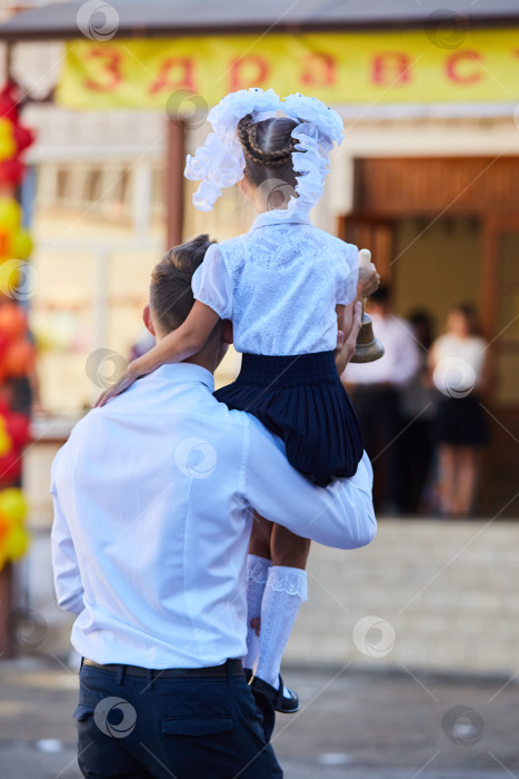 Скачать Старшеклассник держит на руках девочку-первоклассницу и дает первый звонок фотосток Ozero
