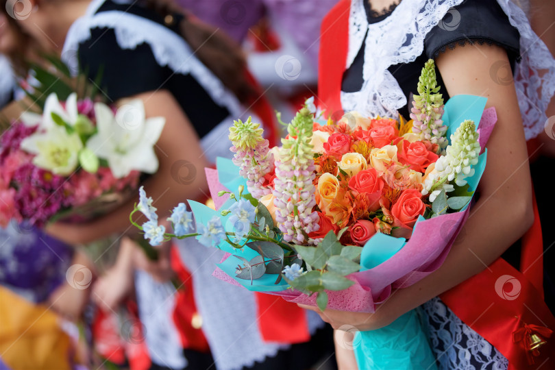 Скачать Руки учеников с цветами на торжестве в честь начала нового учебного года. фотосток Ozero