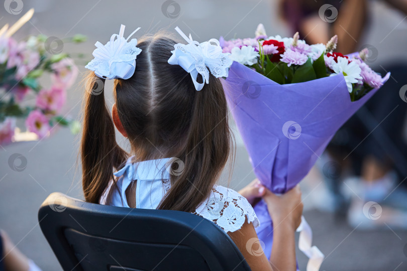 Скачать Руки учеников с цветами на торжестве в честь начала нового учебного года. фотосток Ozero